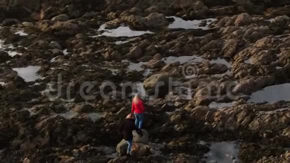 爱尔兰的两个女孩爬过马林海角的岩石海岸视频的预览图