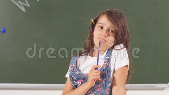 体贴的小微笑女孩拿着铅笔的肖像天才儿童的想法视频的预览图