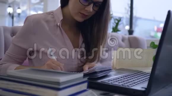 成功的戴眼镜的商务女性会随身携带笔记本电脑并在笔记本电脑上记录商业想法视频的预览图