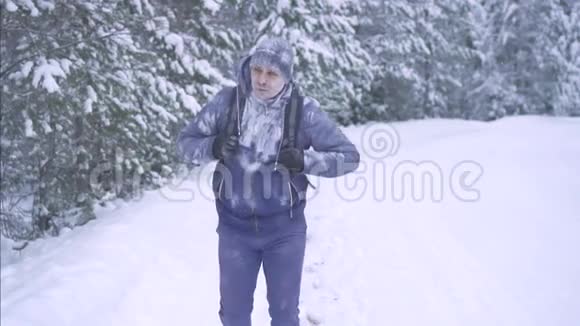 一个冻在雪地里的人背着背包穿过树林视频的预览图