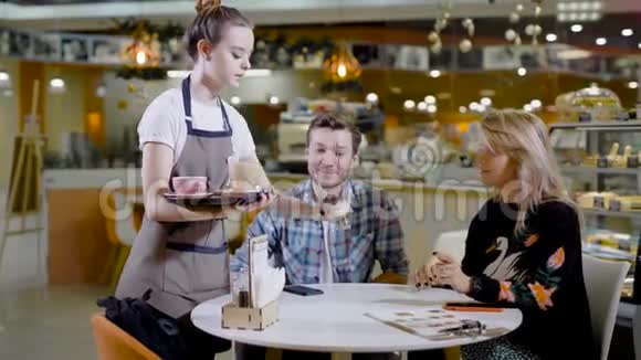 可爱的女服务员咖啡和甜点在舒适的咖啡馆快乐的约会视频的预览图