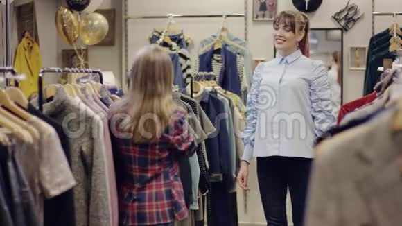 年轻漂亮的一对女人在服装店里找新衣服其中一个正在试穿一件t恤视频的预览图
