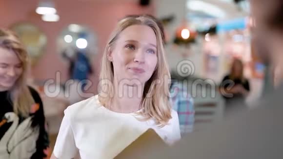 一家咖啡馆的漂亮金发女经理和咖啡师交谈人们站在后面视频的预览图