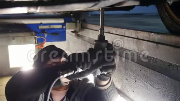 汽车服务厚厚的机械师站在检查坑里用工具拧紧螺丝视频的预览图