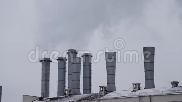 灰色天空背景下工厂屋顶的管道烟雾视频的预览图