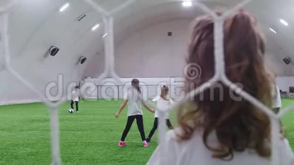 室内足球场小孩子在踢足球网格后面的视图视频的预览图