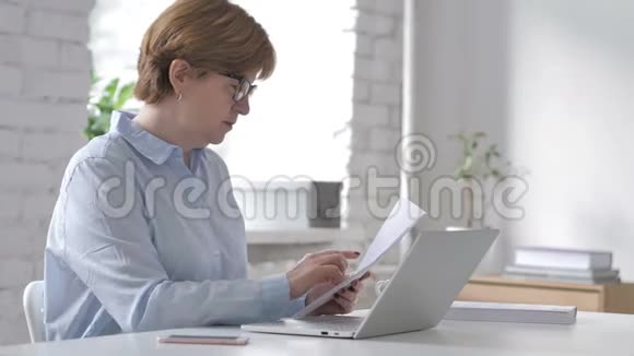 老女人在工作场所忙着做文书工作打字视频的预览图