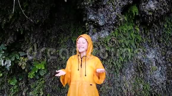 身穿黄色雨衣的年轻女子站着抬起头双手慢动作视频的预览图