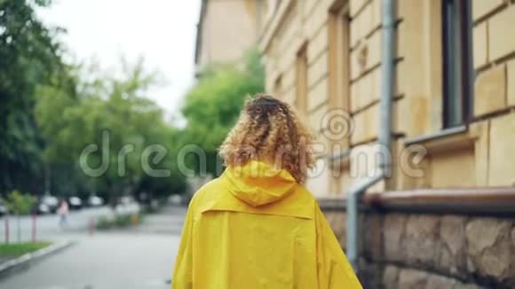 微笑的非洲裔美国妇女穿着鲜艳外套走在街上转向相机和镜头慢镜头的肖像视频的预览图