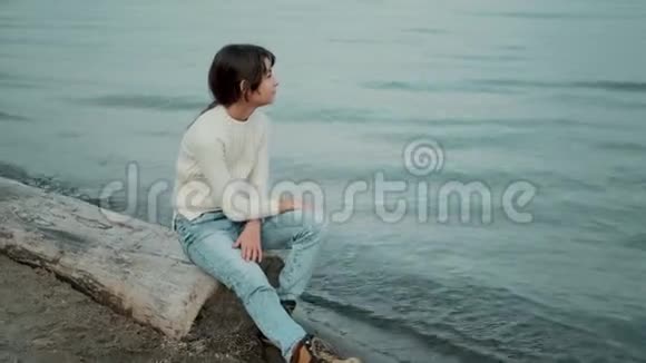小孩子坐在靠近大海的木头上欣赏美丽的景色视频的预览图