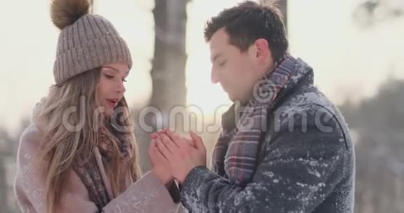 一对相爱的夫妻一个男人用呼吸温暖他的手一个女人冬天在公园里散步的时髦情侣视频的预览图