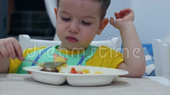 可爱的小孩子坐在圣经里的一张桌子上吃自己的纯净婴儿吃的心甘情愿概念快乐儿童玩具视频的预览图
