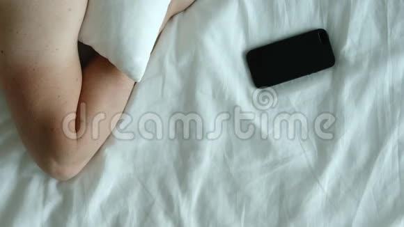 俯视图人类的手在床上拿着一部手机早上就把它关掉视频的预览图