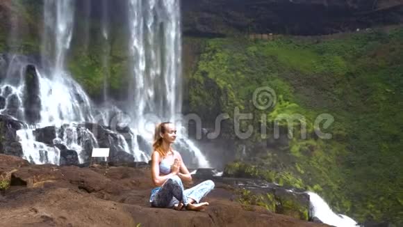 年轻女子在大型岩石上做普拉纳亚瑜伽练习视频的预览图
