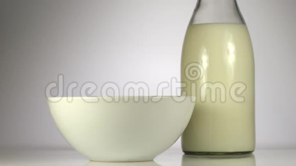 慢动作麦片片落在桌子上牛奶旁边的白色盘子里视频的预览图