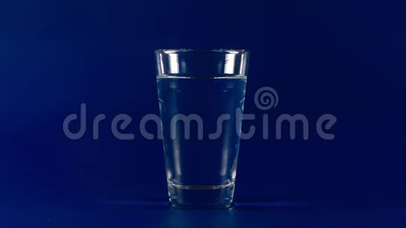 在蓝色背景下饮用杯中的清水停止运动视频的预览图