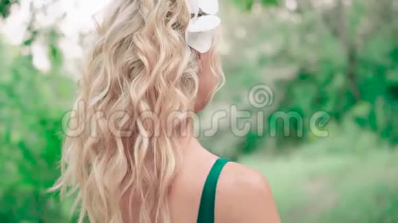 美丽的金发女孩一个美丽的卷发站在镜头前慢慢地转过身尴尬视频的预览图