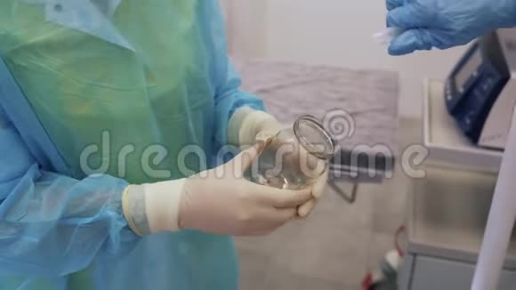 医生的特写双手将消毒剂倒入护士手中的玻璃瓶中视频的预览图