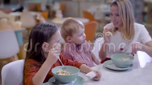 美丽的金发母亲和儿子和女儿在舒适的咖啡馆吃周末视频的预览图