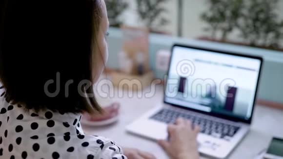 一个年轻的黑发女人坐在咖啡馆里在她的笔记本电脑上冲浪一个人空闲时间视频的预览图