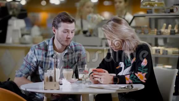 一对可爱的夫妇在咖啡馆里男朋友和女朋友在舒适的咖啡馆里约会吃甜点和喝咖啡视频的预览图
