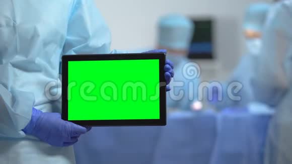医院手术过程中护士手拿平板电脑和绿色屏幕视频的预览图