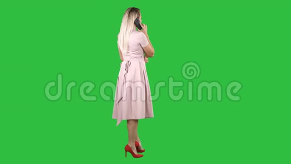 站着的年轻漂亮女孩在绿色的屏幕上打电话色度键视频的预览图
