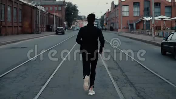 运动员跑在街中央背景镜头慢动作在电车轨道之间的远视角视频的预览图