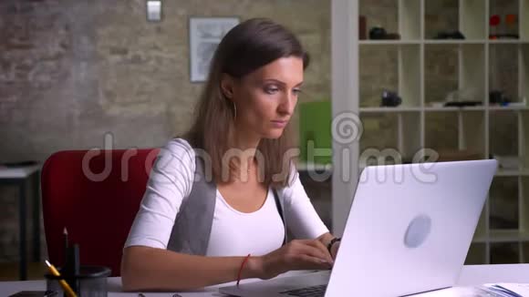 漂亮的女办公室工作人员在笔记本电脑上打字在电话上查看信息并为此有一个创造性的想法视频的预览图