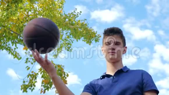 一个十几岁的年轻人在篮球场上把球旋在手指上视频的预览图
