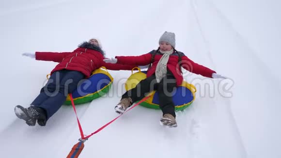 快乐的少女们去却雪道在冬天的雪山上伸直双臂在飞翔和欢笑快乐视频的预览图