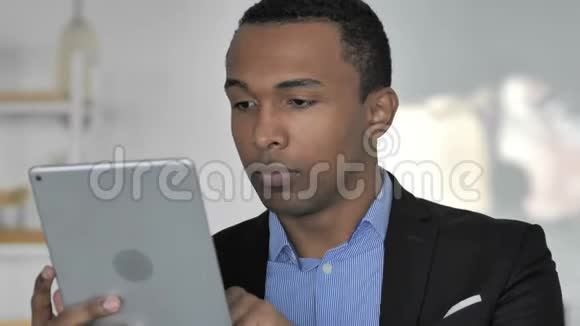 非裔美国商人在使用平板电脑时对结果感到惊讶的特写镜头视频的预览图