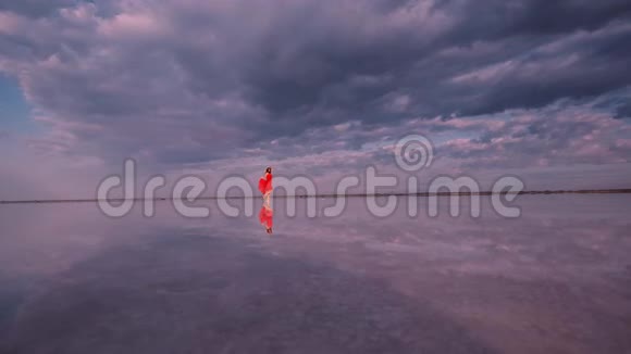 旅游女孩正沿着一个反映云层的盐湖散步视频的预览图