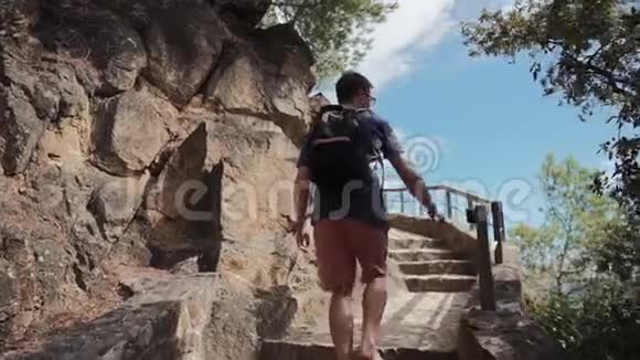 男游客在夏日的悬崖上爬过老石楼梯视频的预览图