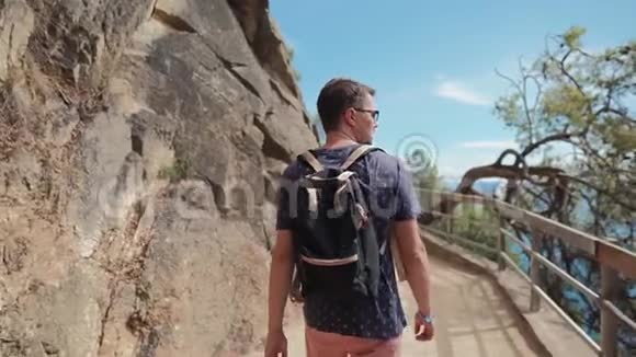 阳光明媚的一天成年男子独自走在山坡上的狭窄小路上后景视频的预览图