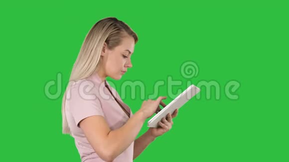 女孩拿着数字平板电脑在绿色屏幕上搜索一些东西Chroma键视频的预览图
