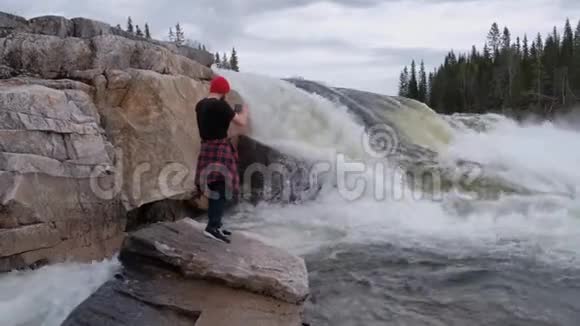游客站在瀑布下拍摄水流如何视频的预览图