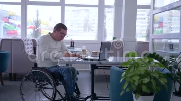 网上购物成功的残疾人在轮椅上戴眼镜用信用卡支付网上付款视频的预览图