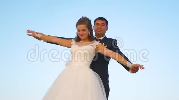 新娘和新郎在蓝天上跳舞一对相爱的夫妇的团队合作浪漫的男人和女人盘旋在视频的预览图