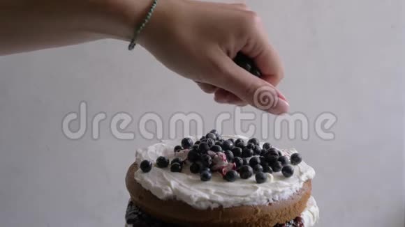 女性用蓝莓装饰蛋糕特写慢动作视频的预览图