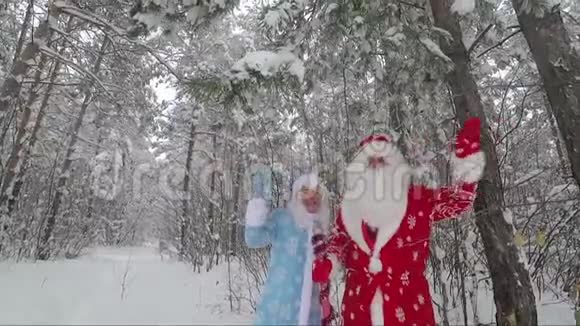 圣诞老人和孙女在雪松森林里挥舞着手慢动作视频视频的预览图