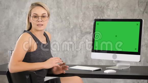 漂亮的年轻女人戴着眼镜对着镜头说话绿屏模拟显示视频的预览图