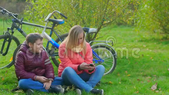 十几岁的男孩和他的母亲坐在草地上对智能手机的依赖视频的预览图