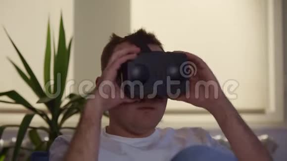 男性在家坐着使用VR耳机视频的预览图