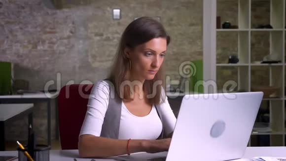 漂亮的女办公室工作人员在笔记本电脑上打字和发信息微笑着感到惊讶和满意视频的预览图