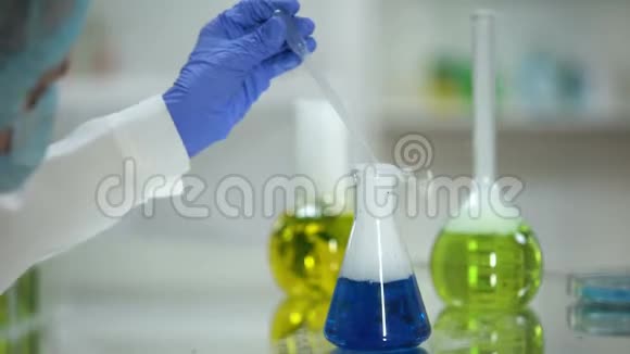 从烧瓶中取蓝色物质样品的化验师洗涤剂分析试验视频的预览图