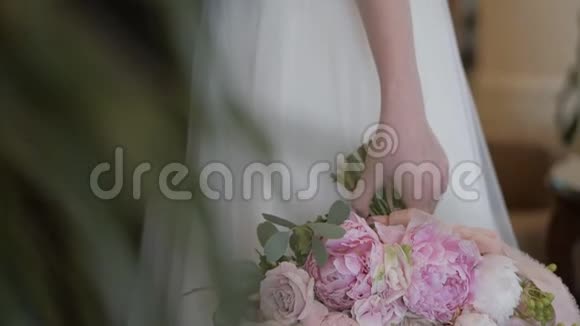新娘穿着象牙色的婚纱手里捧着一束美丽的粉红色牡丹花视频的预览图