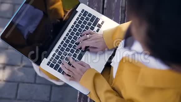 关闭电脑键盘上女性手打字的顶部视图户外年轻的女商人坐在长凳上视频的预览图