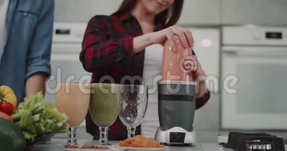 一对年轻的纯素食夫妇在早上为所有的家庭做冰沙女人把冰沙倒进一个大玻璃杯里放在一个大玻璃杯里视频的预览图