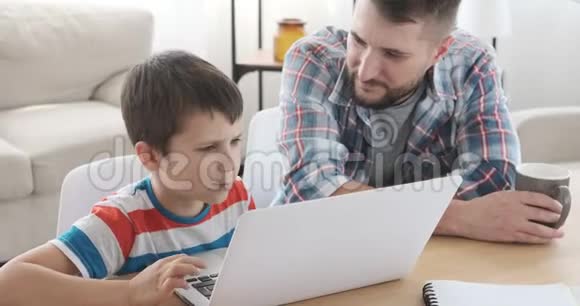 父亲在家里教儿子使用笔记本电脑视频的预览图